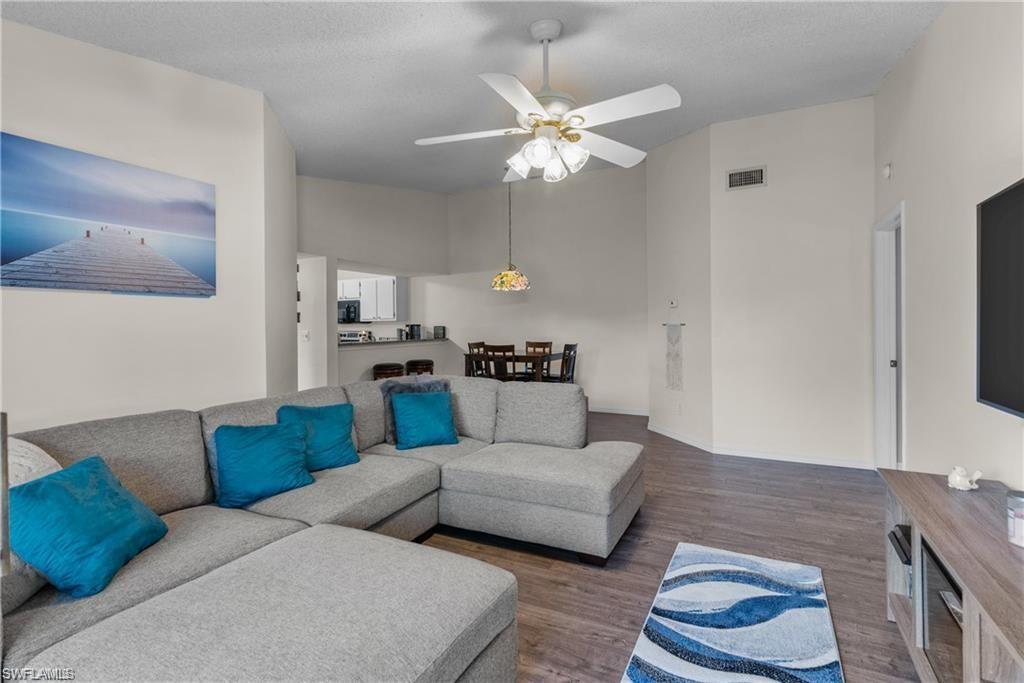 Living room featuring ceiling fan, dark hardwood / wood-style flooring, and a towering ceiling