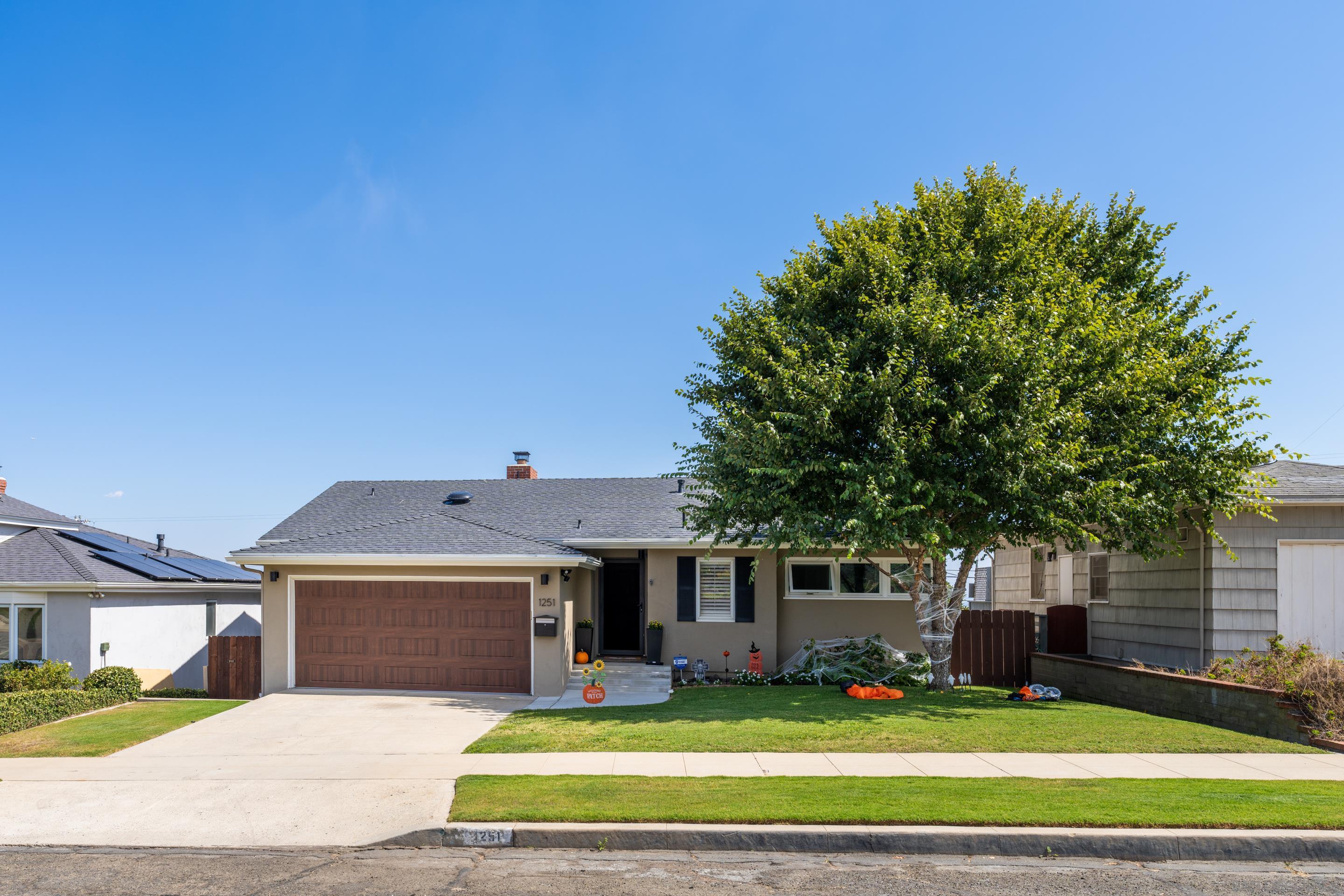 a front view of a house with yard and large tree