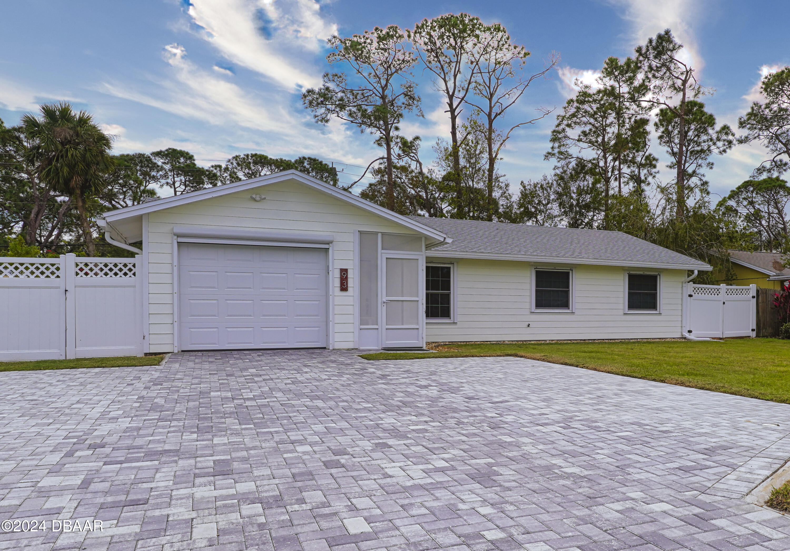 a front view of house with yard and trees in the background