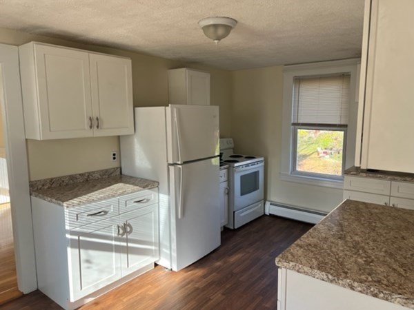 a kitchen with granite countertop a refrigerator a stove a sink and white cabinets