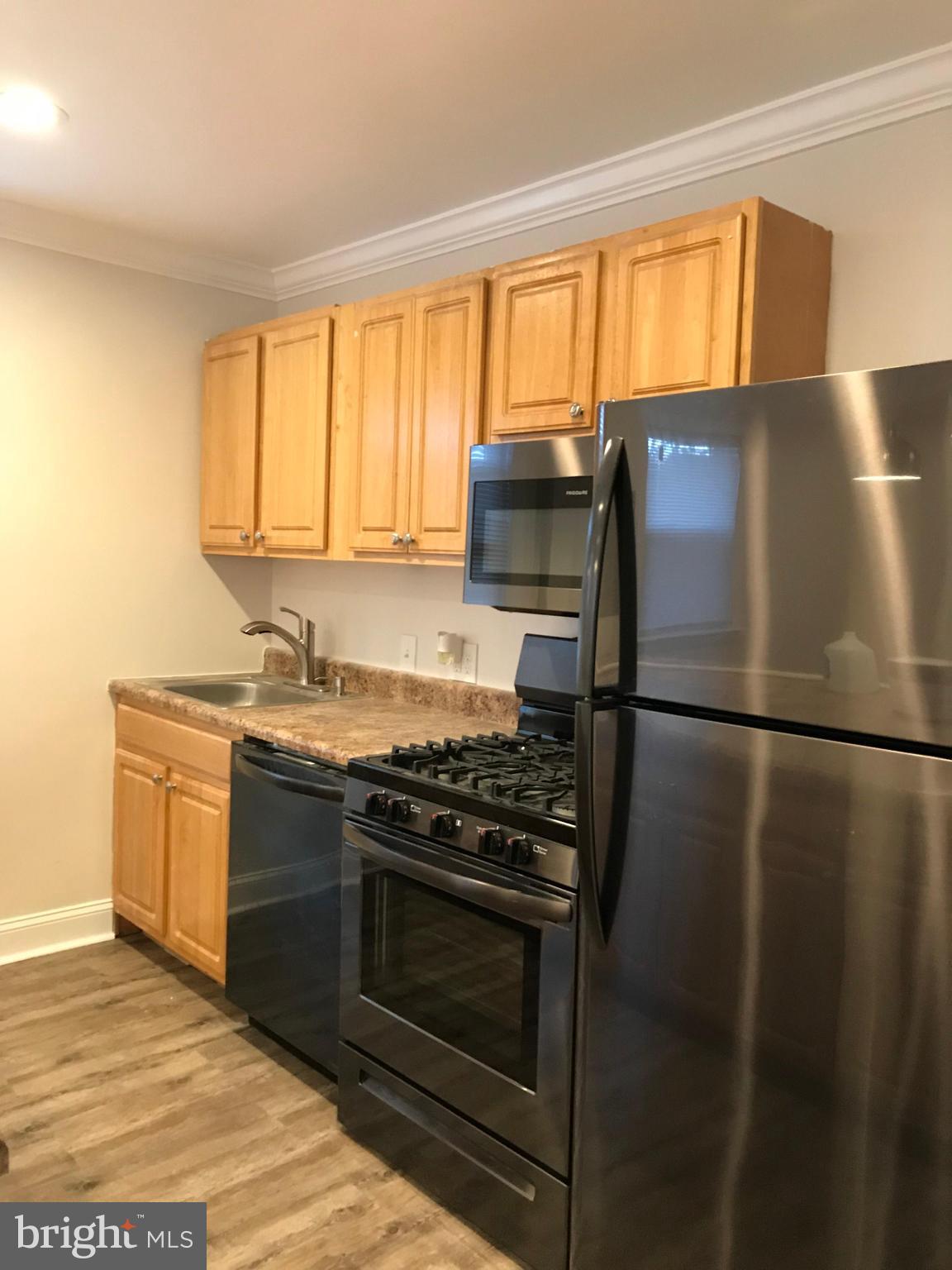 a kitchen with granite countertop a refrigerator stove and sink