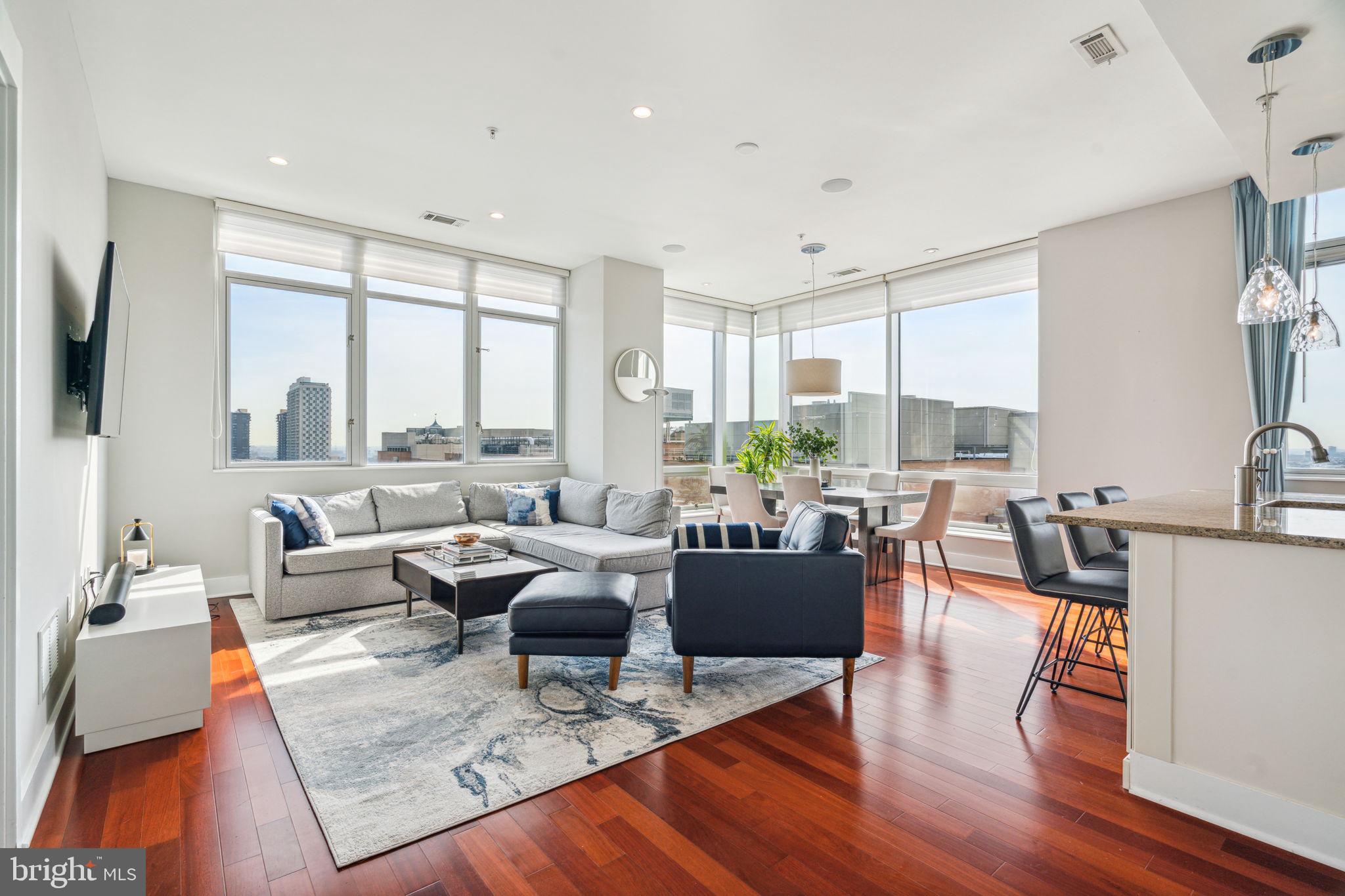 a living room with furniture large window and wooden floor