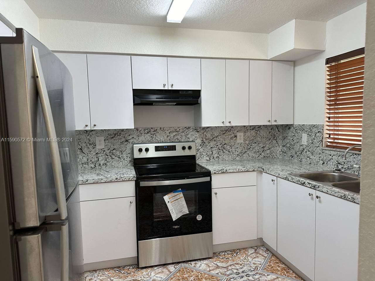 a kitchen with stainless steel appliances granite countertop a stove a refrigerator and a sink