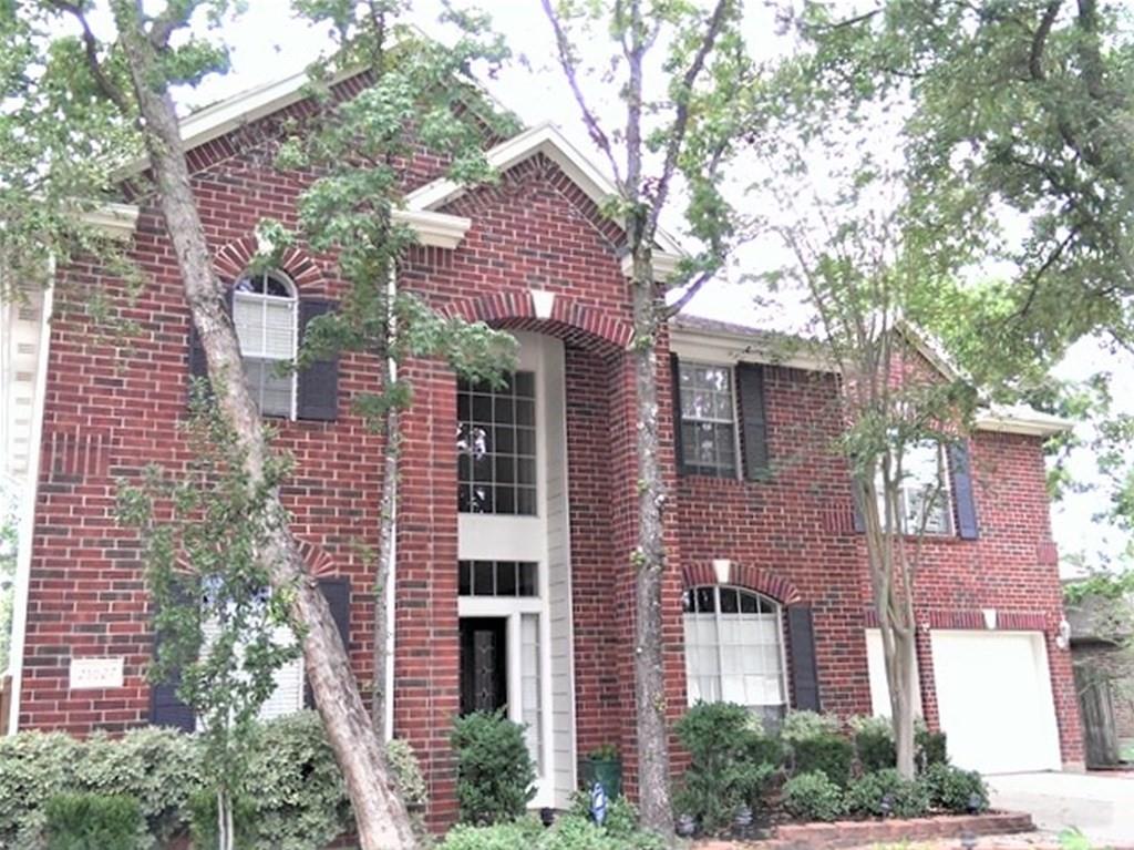 front view of a brick house with a large windows and a large tree