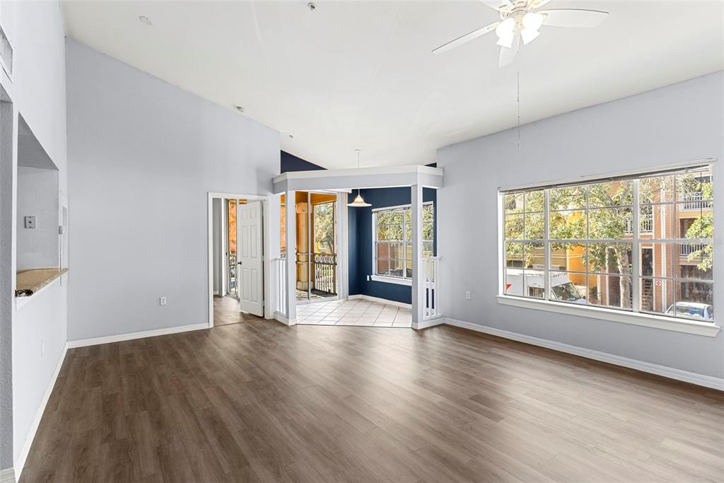 an empty room with wooden floor and large windows