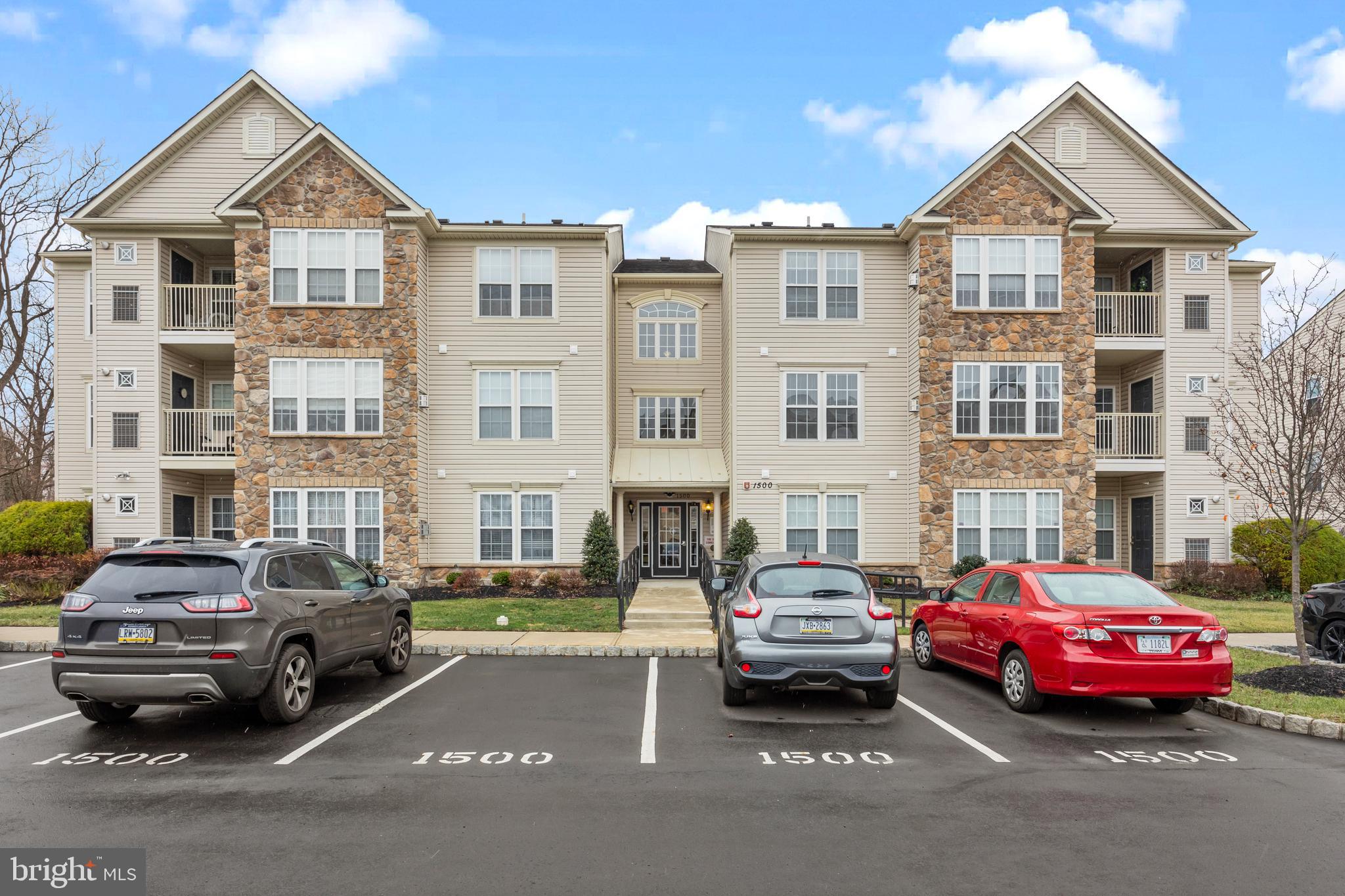 a front view of a residential apartment building with cars parked