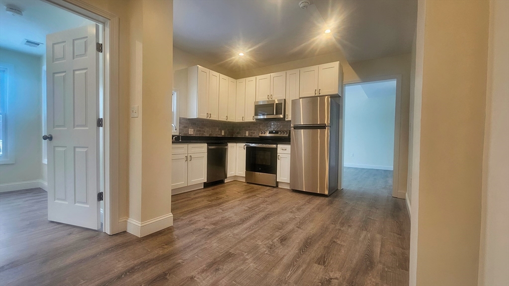 a kitchen with stainless steel appliances a refrigerator and wooden floor