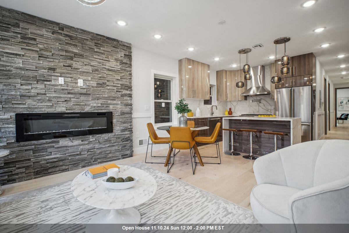 a living room with stainless steel appliances furniture a rug and a kitchen view