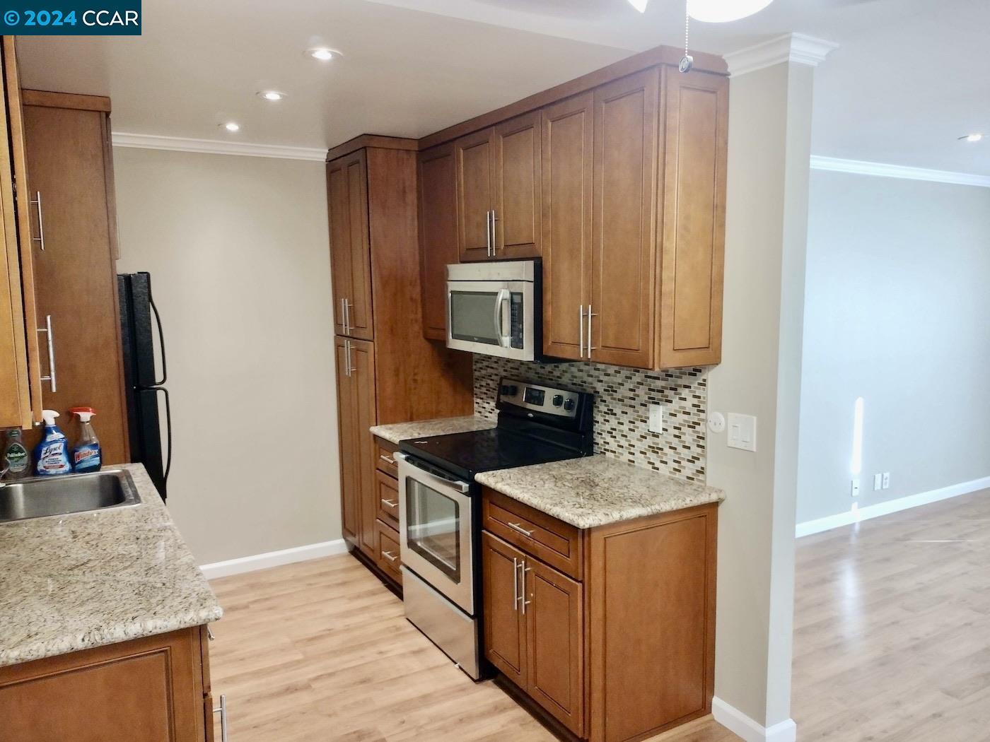 a kitchen with granite countertop cabinets stainless steel appliances and wooden floor