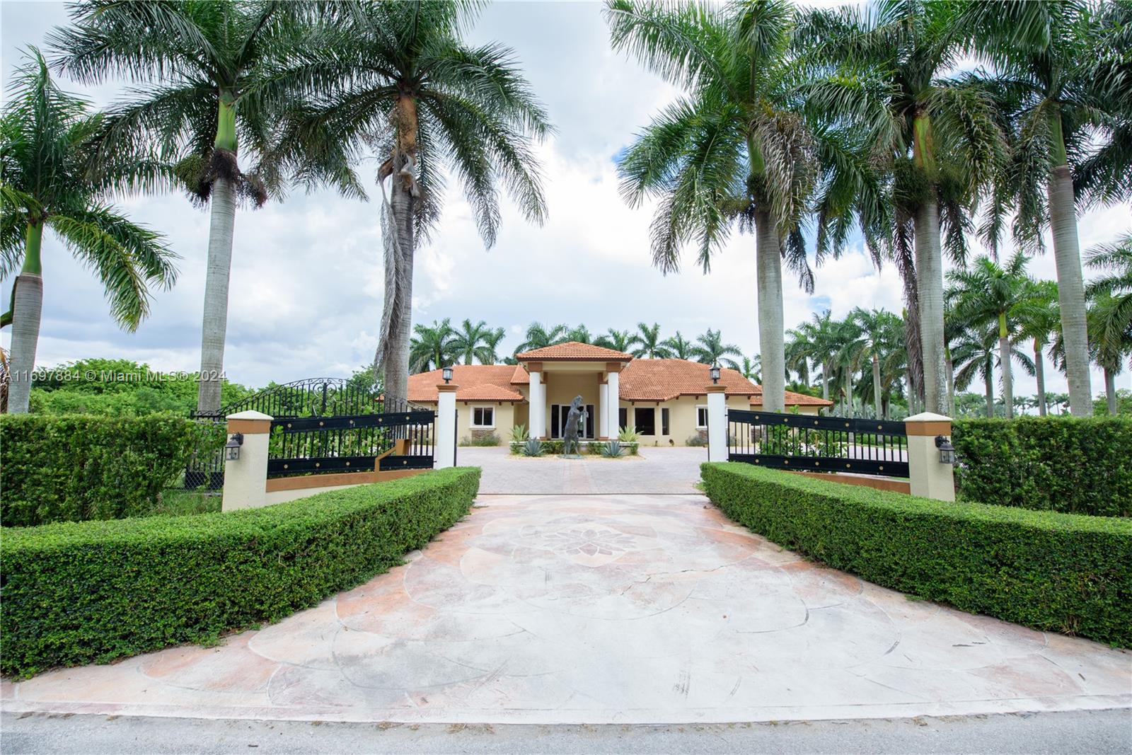 a front view of a house with a garden and palm trees