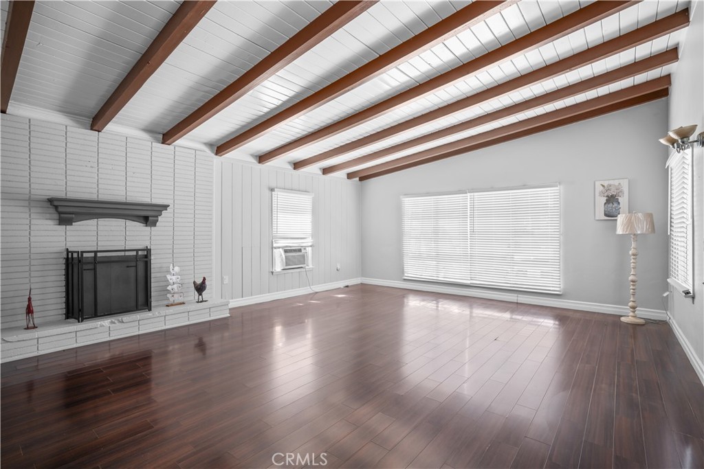 a view of an empty room with wooden floor and a fireplace