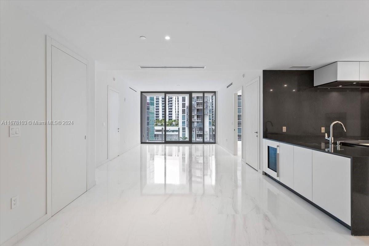 a large white kitchen with sink a refrigerator and window