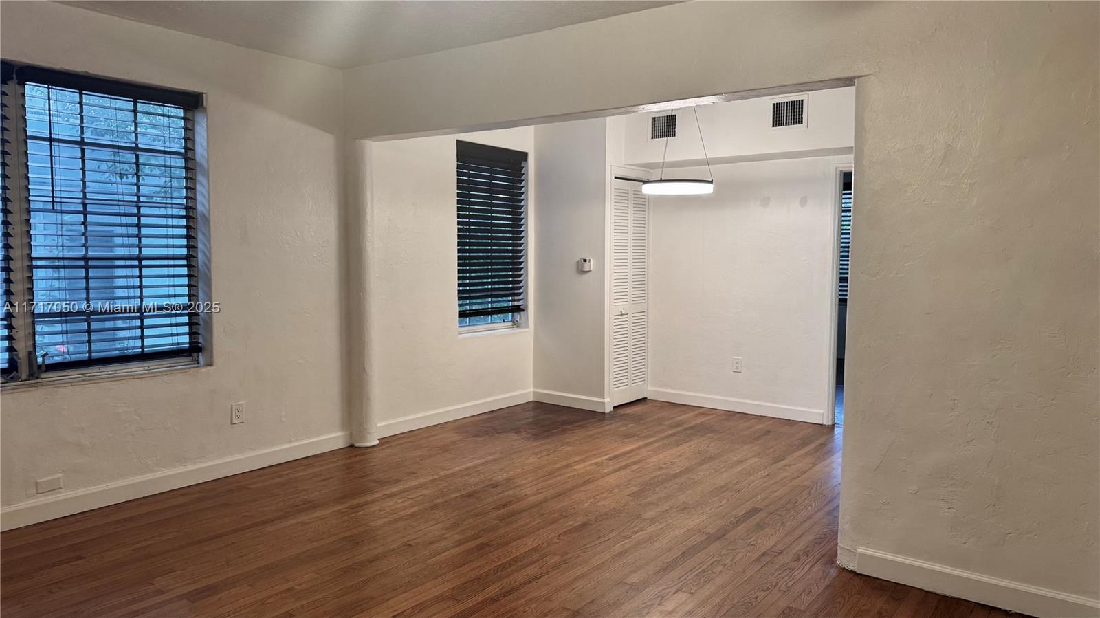 an empty room with wooden floor closet and windows