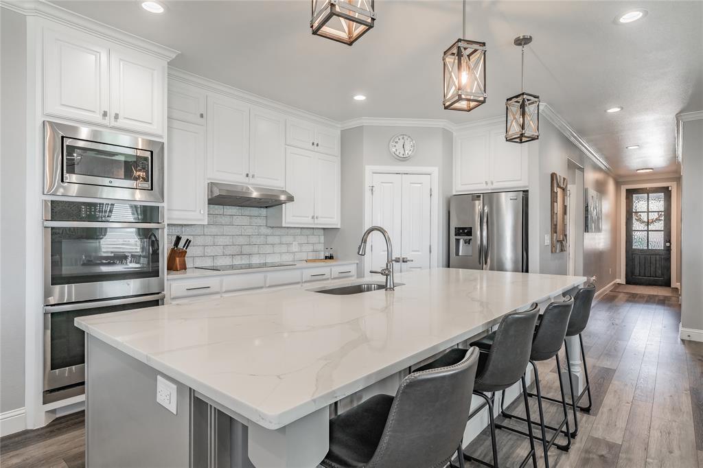 a kitchen with stainless steel appliances granite countertop a sink a stove and chairs