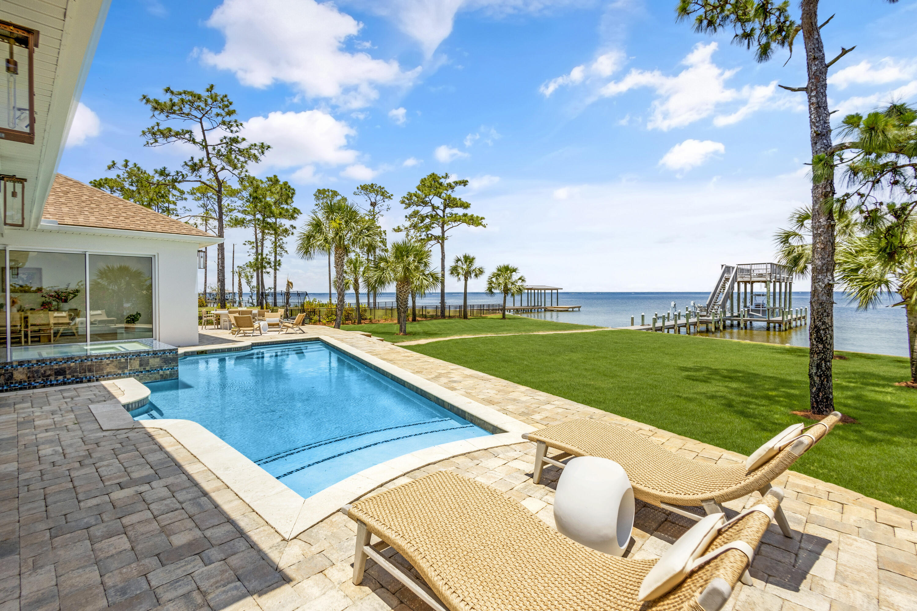 a view of a swimming pool and lounge chairs in back yard of the house