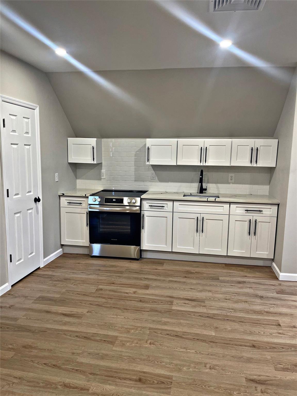 a kitchen with stainless steel appliances granite countertop a stove a sink and white cabinets