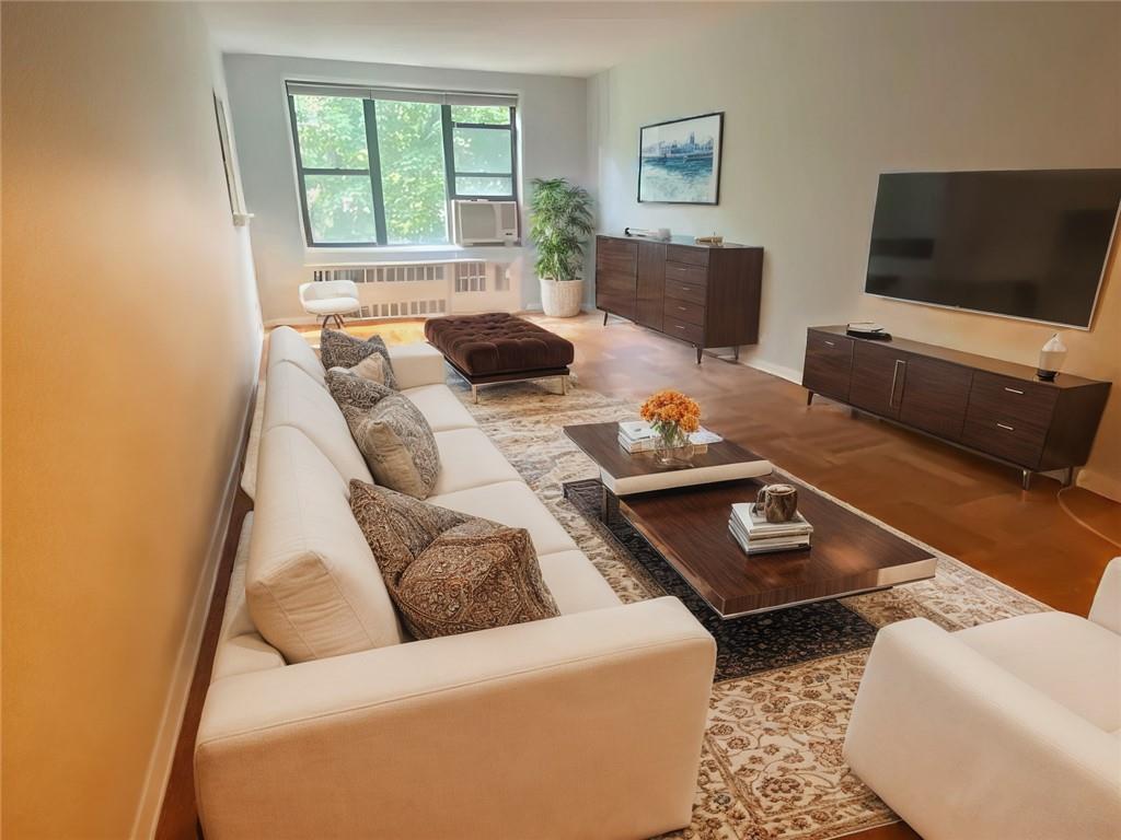 Living room featuring cooling unit, radiator heating unit, and light wood-type flooring