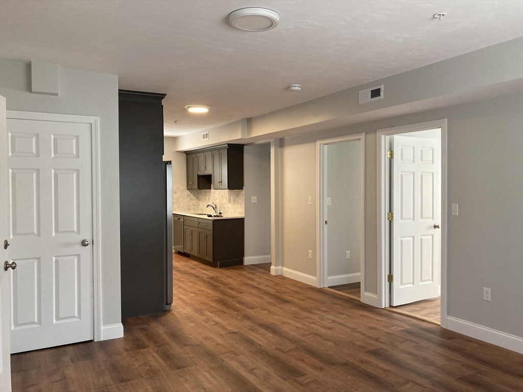 a view of a kitchen with refrigerator and wooden floor