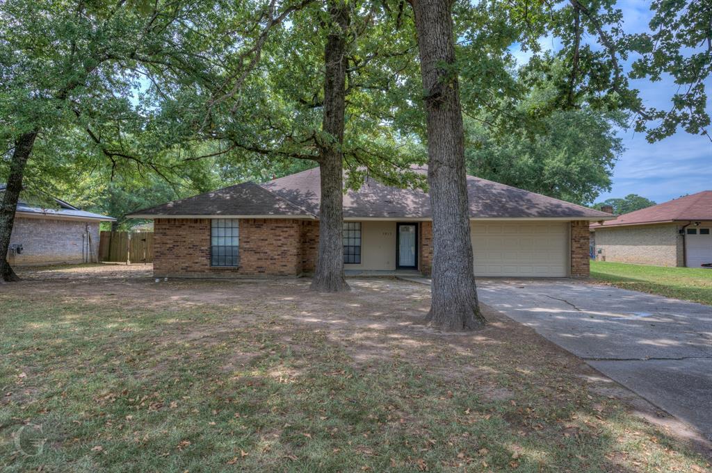 front view of a house with a yard and an trees