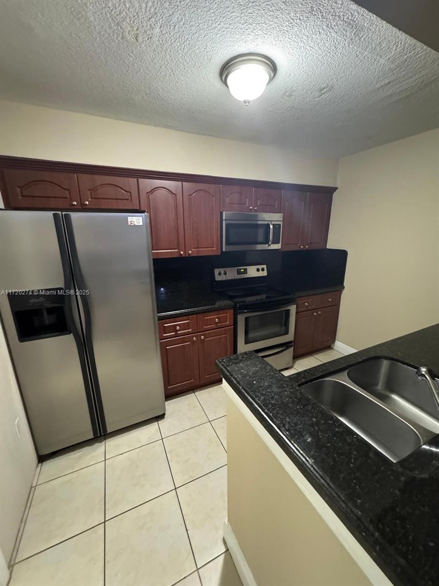 a kitchen with granite countertop a refrigerator and a sink