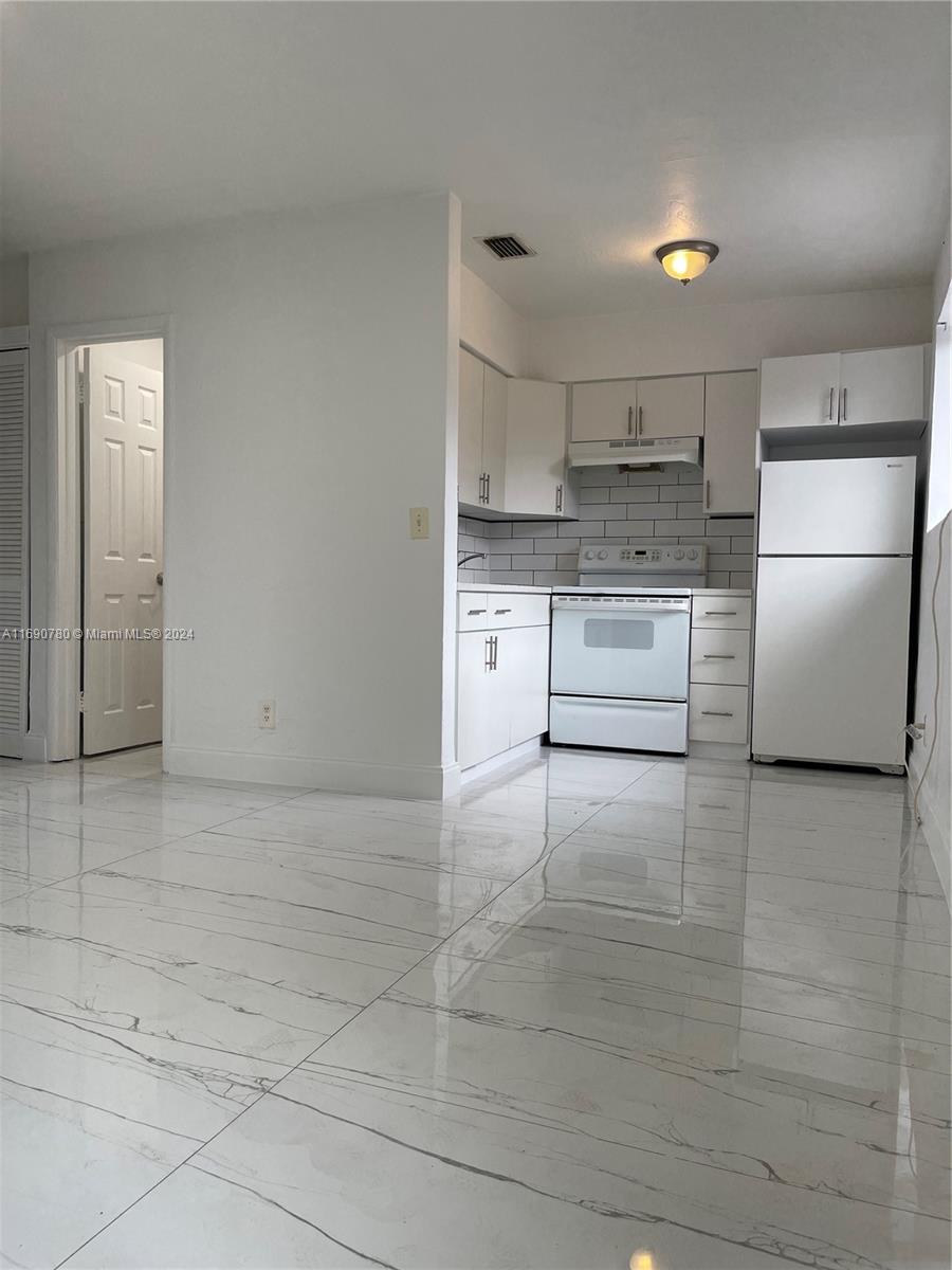 a kitchen with a refrigerator and white cabinets