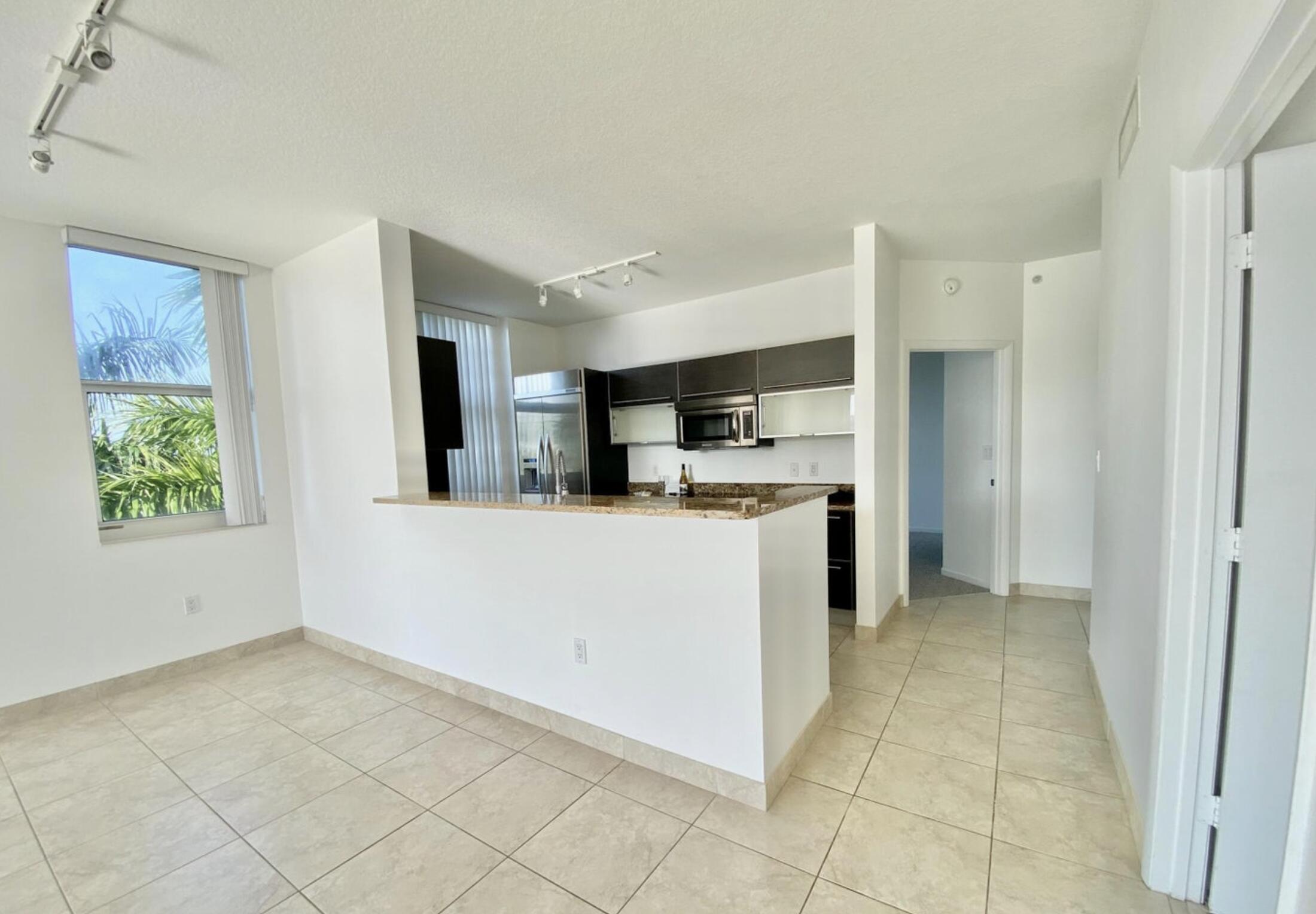 a view of kitchen with stainless steel appliances kitchen island granite countertop white cabinets and window