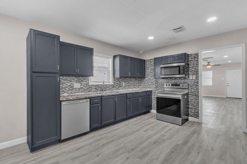 a kitchen with granite countertop a sink cabinets and stainless steel appliances