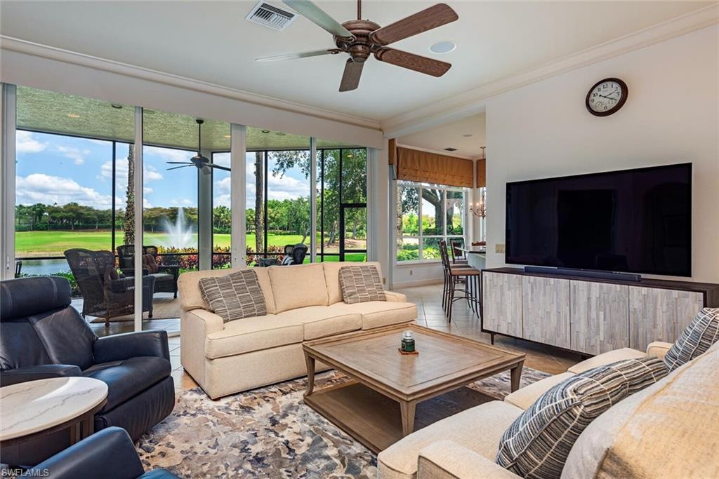 a living room with couches a coffee table and a flat screen tv with a large window