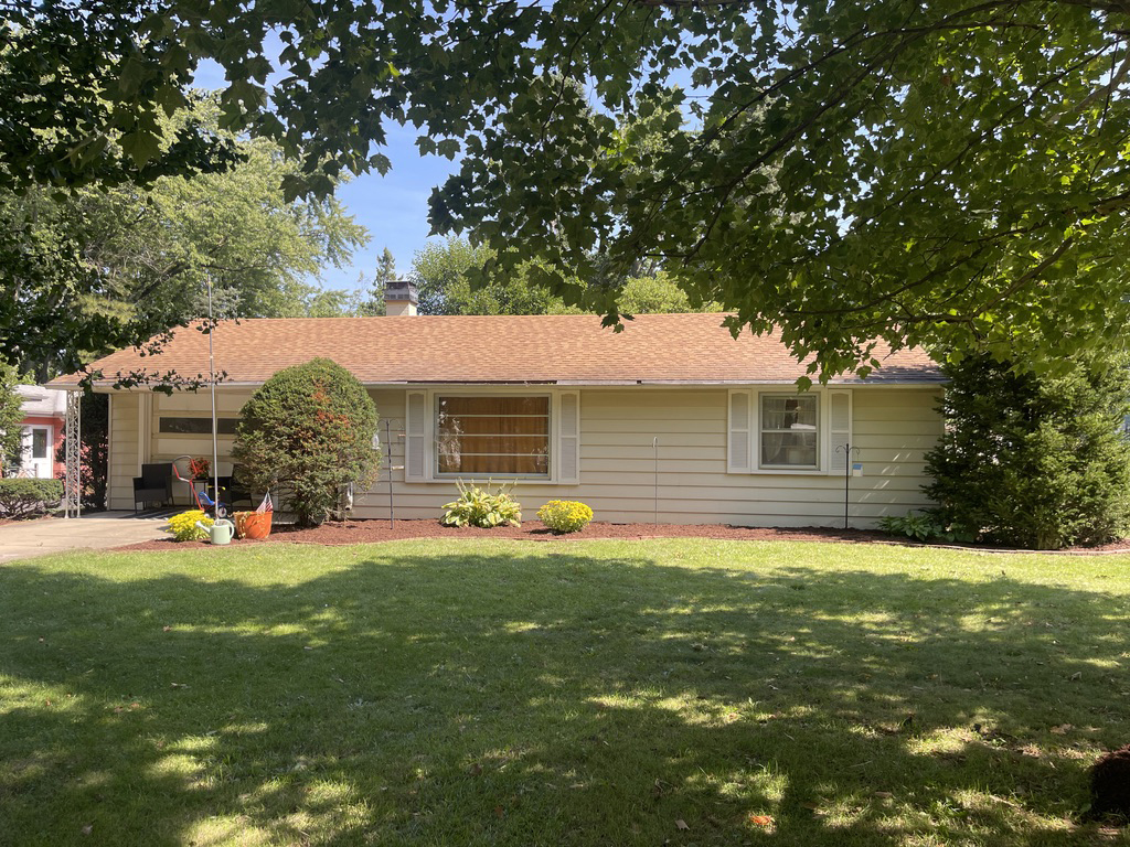 a front view of house with yard and trees in the background