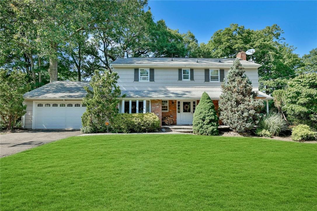 Colonial-style house featuring a garage and a front yard