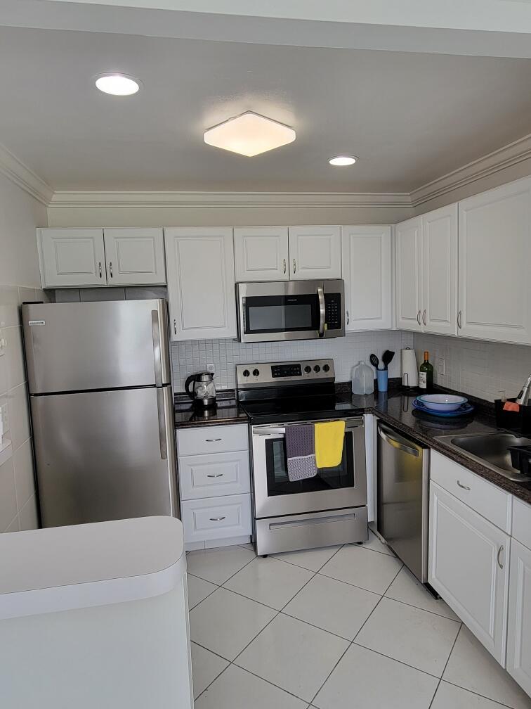 a kitchen with a refrigerator a microwave a sink and cabinets