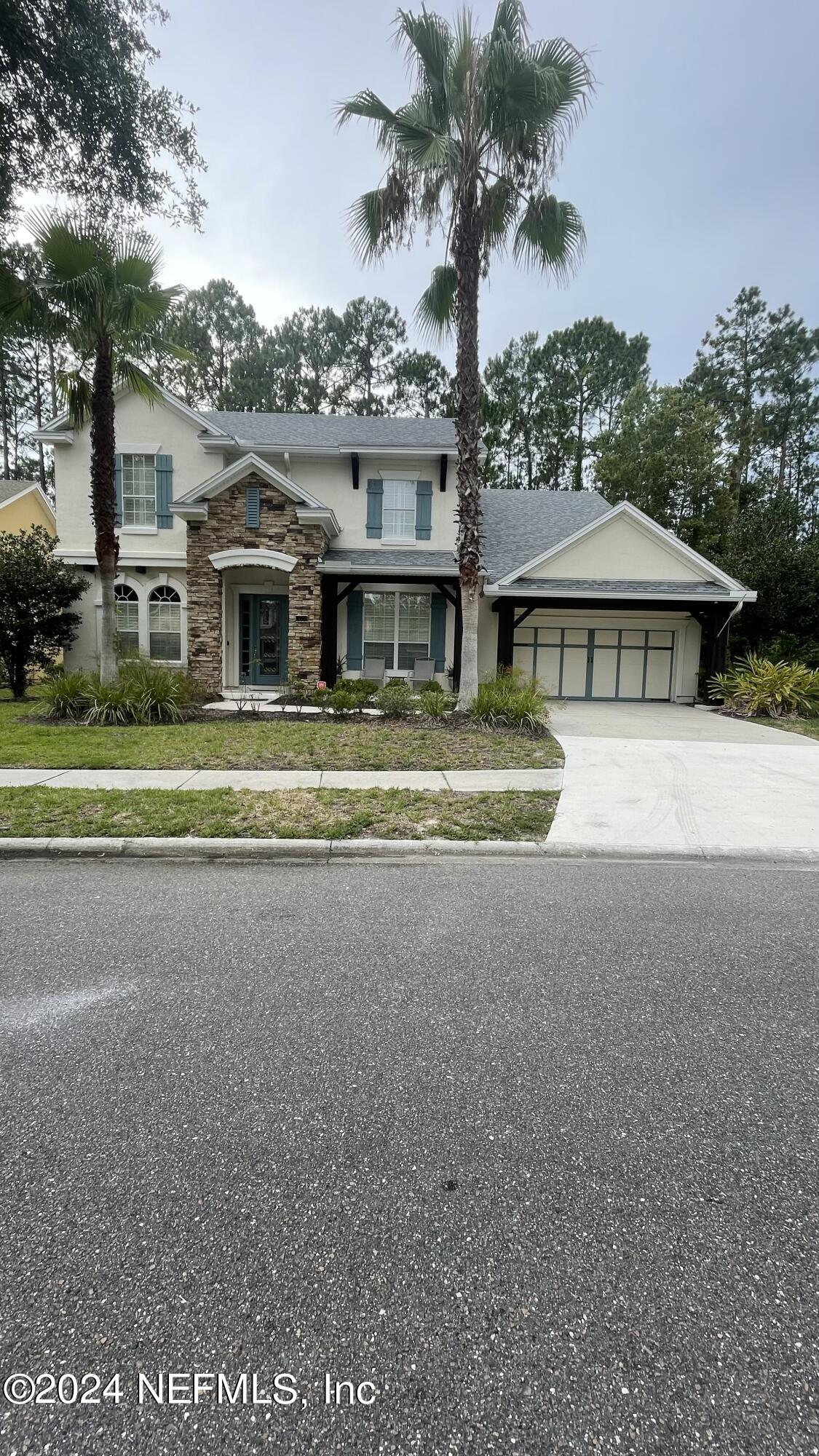 a front view of a house with a garden and trees