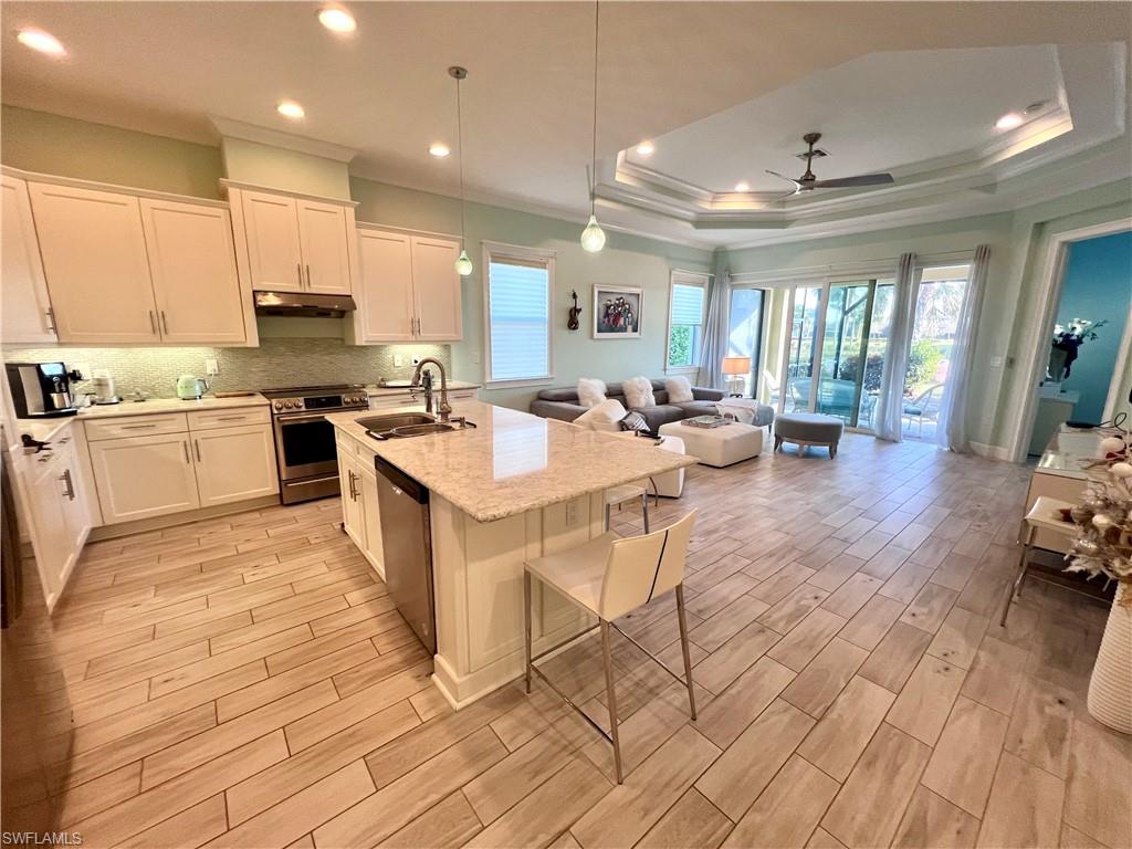 a large white kitchen with lots of counter top space and stainless steel appliances