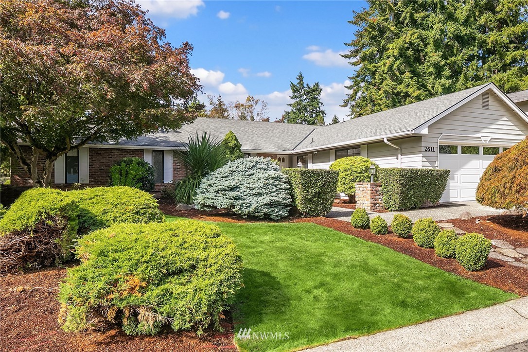 a view of a house with a big yard plants and large tree