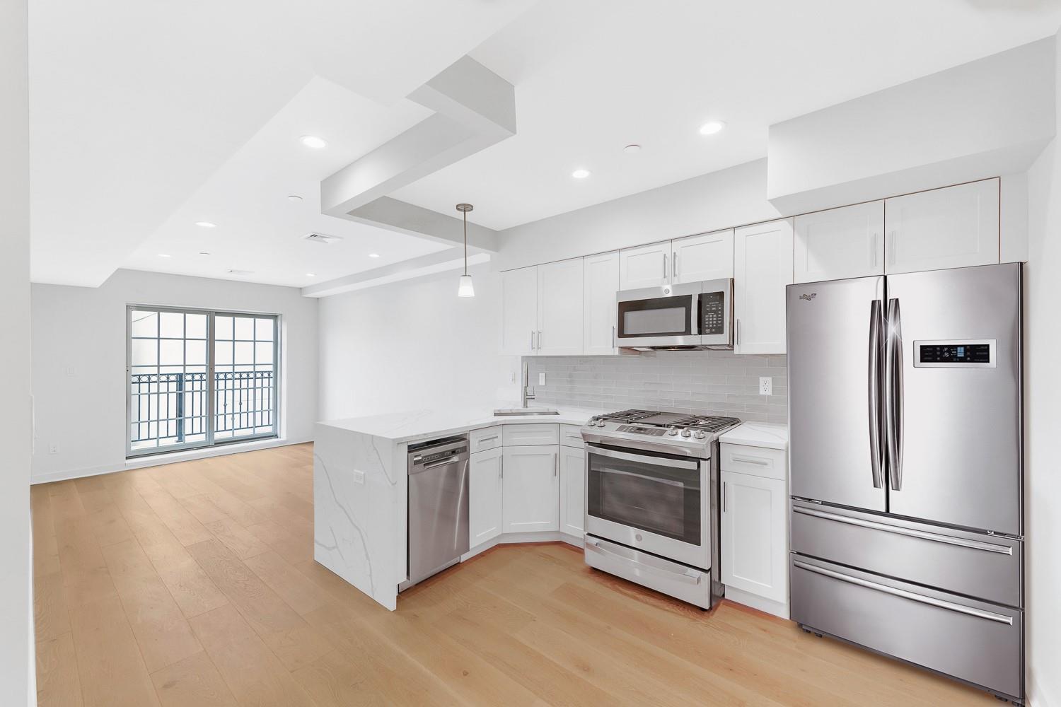 Kitchen with appliances with stainless steel finishes, light wood-type flooring, tasteful backsplash, light stone counters, and white cabinetry