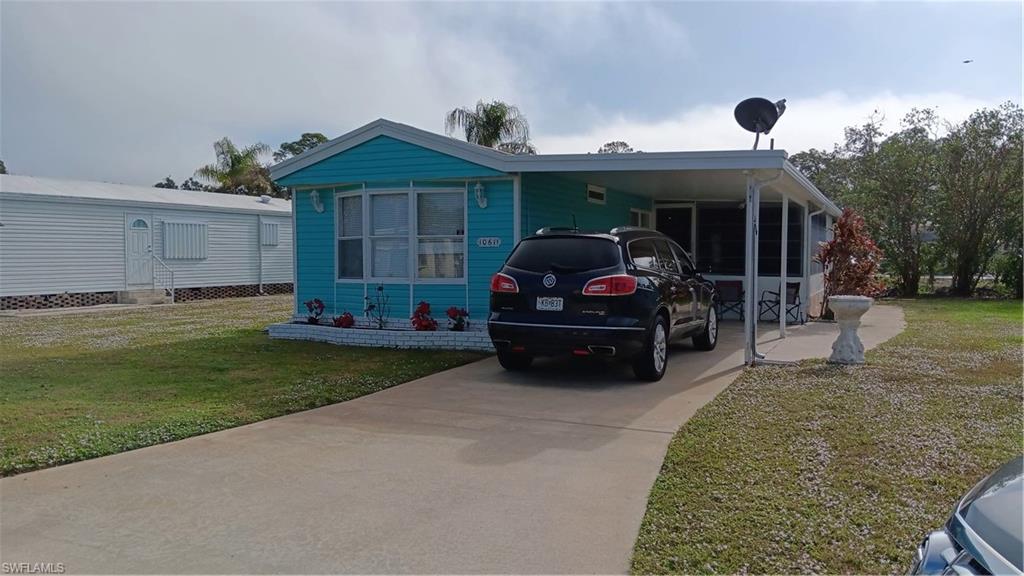 View of front of property with a front yard and a carport