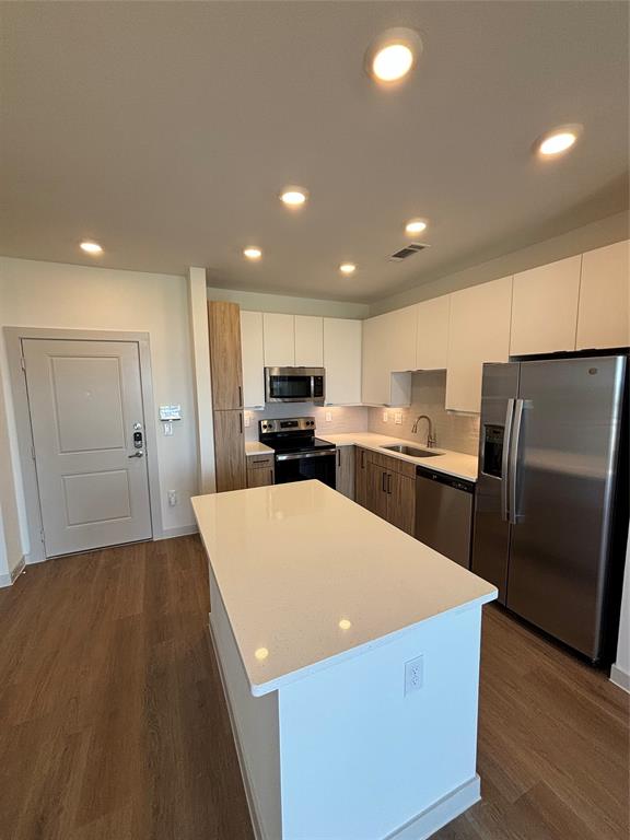 a large kitchen with stainless steel appliances kitchen island a large counter top and wooden floors