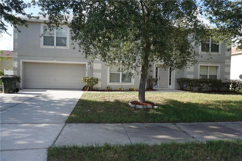 a front view of a house with a yard and trees