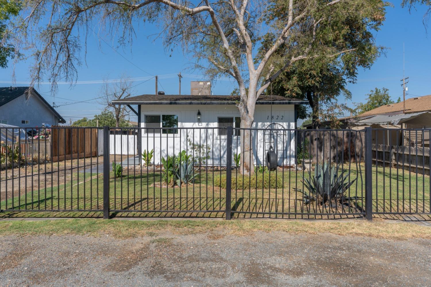 a view of a house with a small yard and a large tree