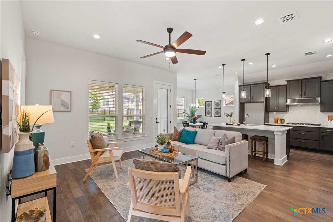 a living room with furniture kitchen view and a large window