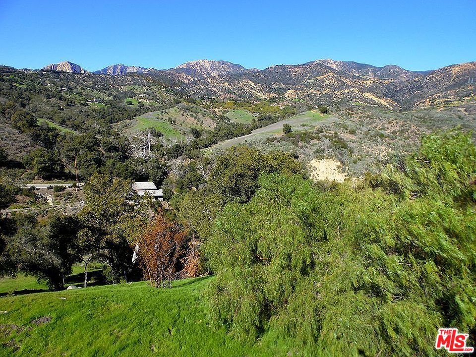 a view of a lush green field with mountains in the background