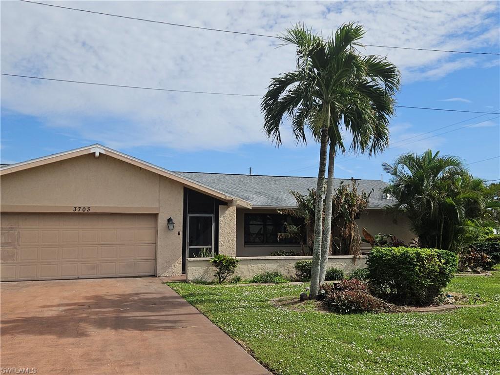 Ranch-style home featuring a garage and a front lawn