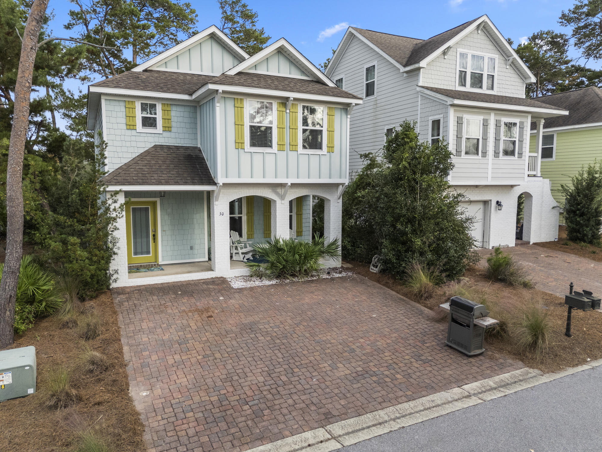 a view of a white house next to a yard with potted plants