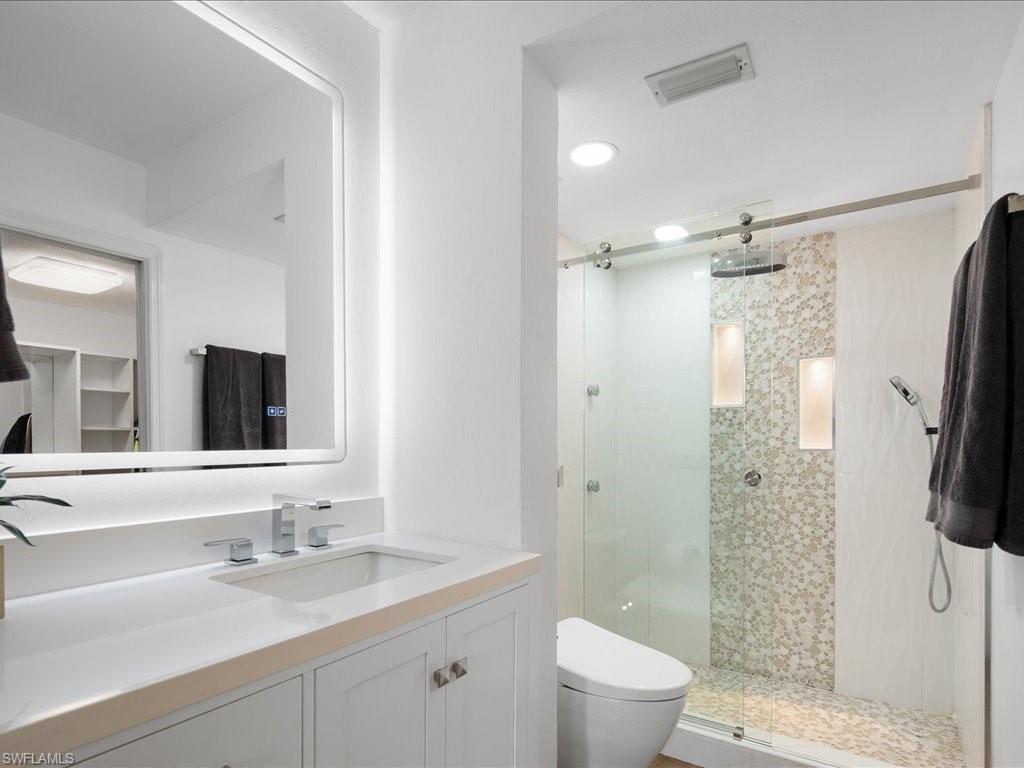 a bathroom with a granite countertop sink a toilet and shower