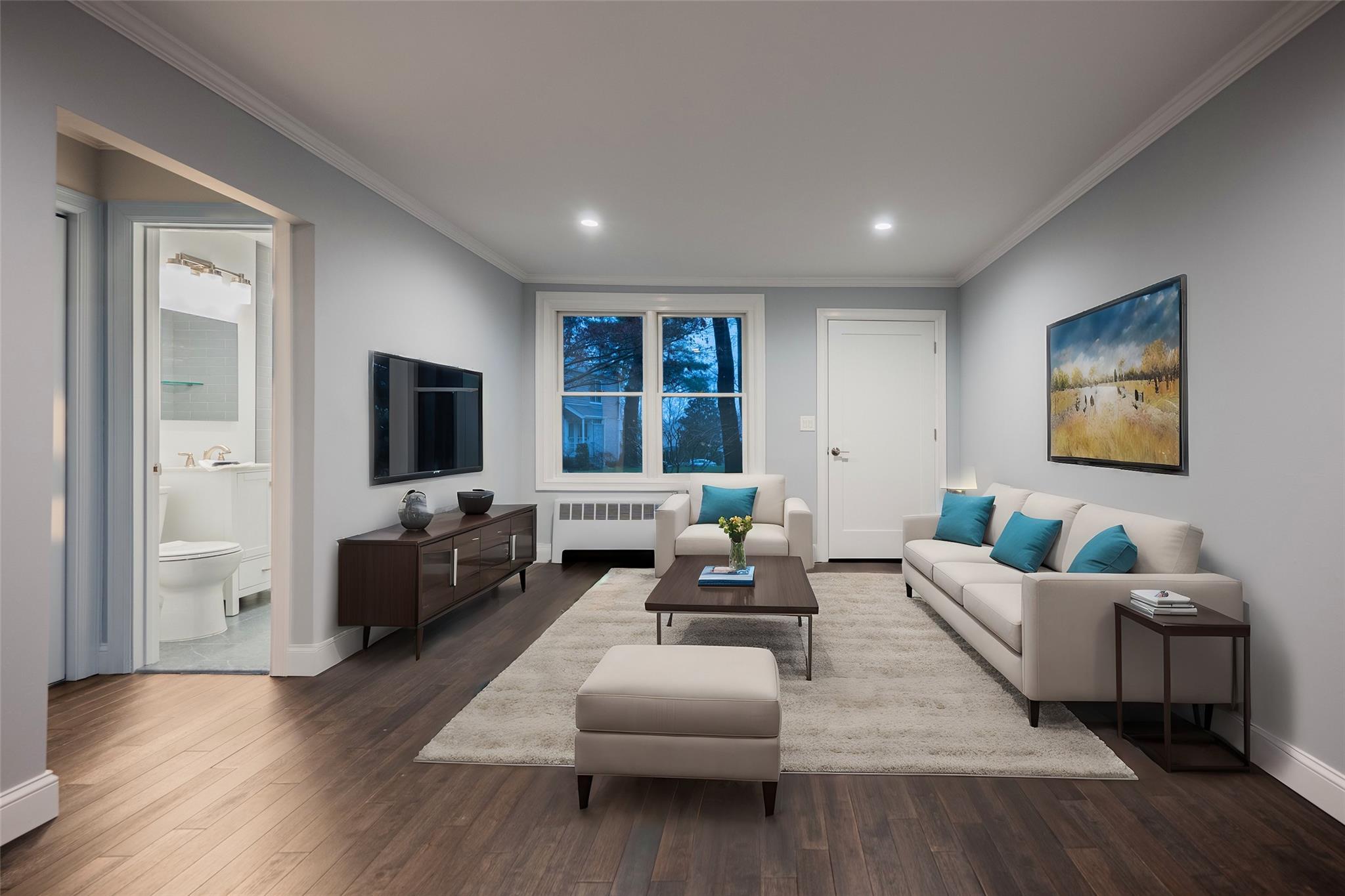 Living room featuring dark hardwood / wood-style flooring, crown molding, and radiator