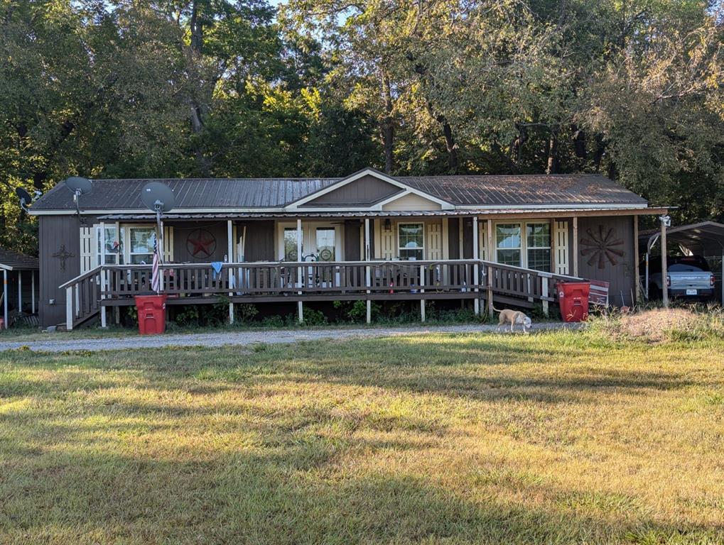 a view of a house with a yard deck and a large tree