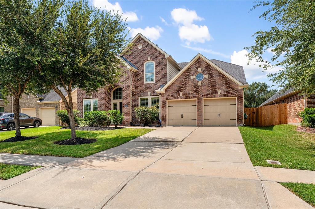 Charming two-story brick home featuring an attached three-car garage, a manicured lawn with mature trees, nestled in the master planned community of River Park West.