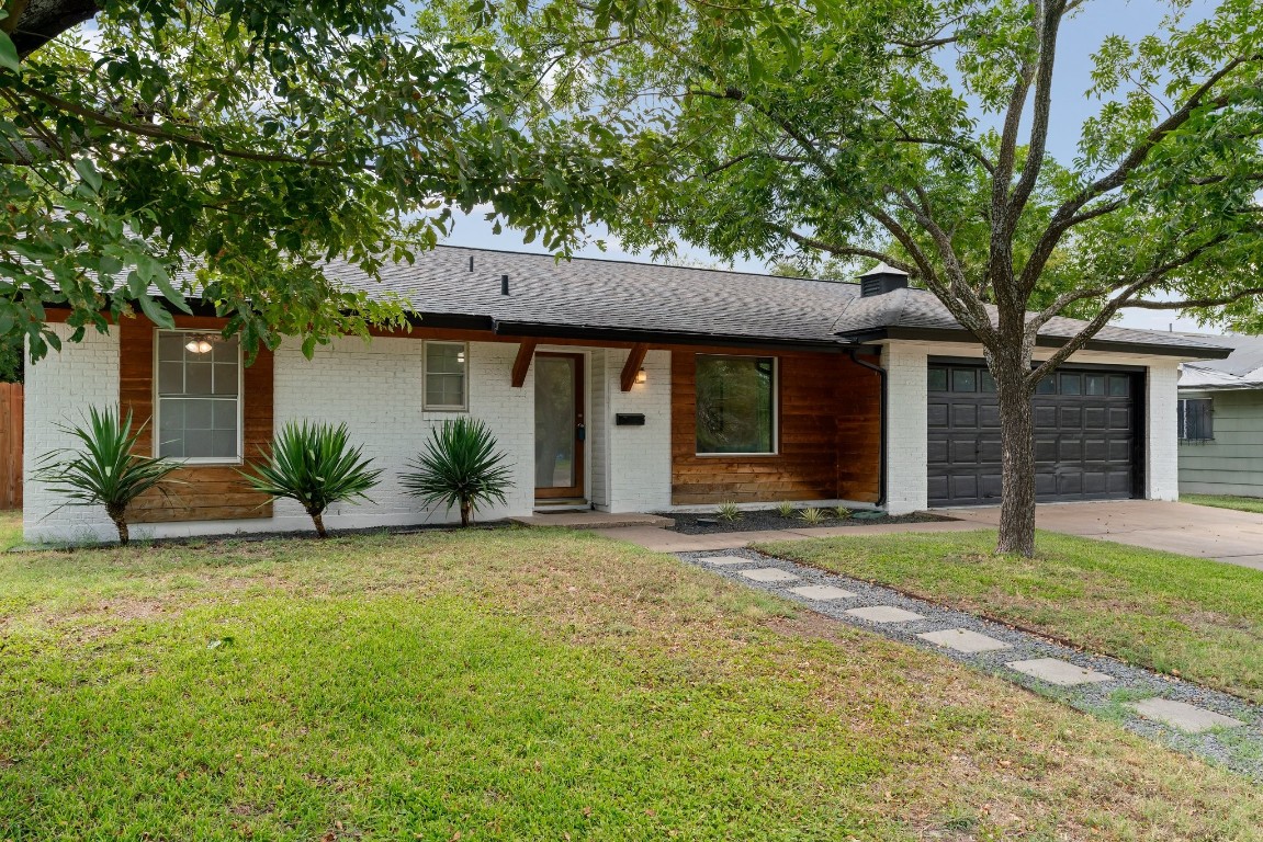 a front view of a house with a garden and a tree