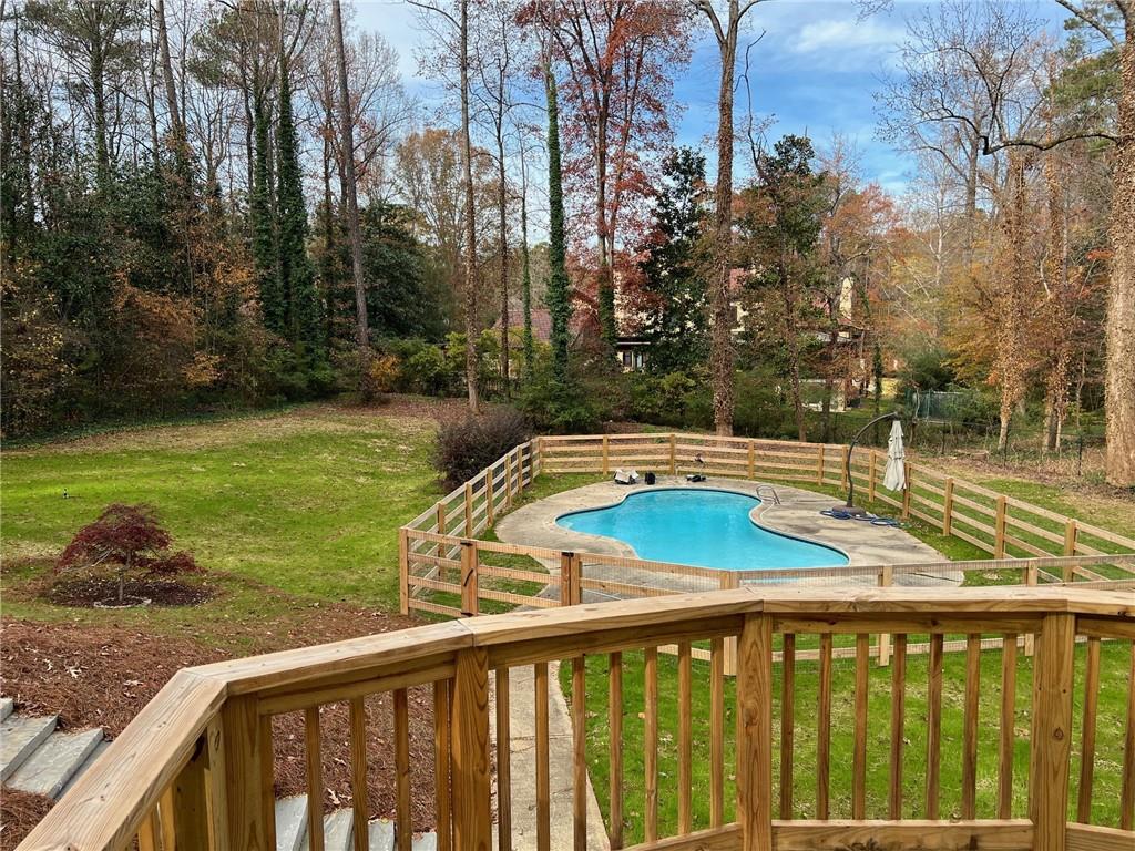 a view of a swimming pool with a patio and a yard