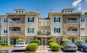 a front view of a residential apartment building with cars parked